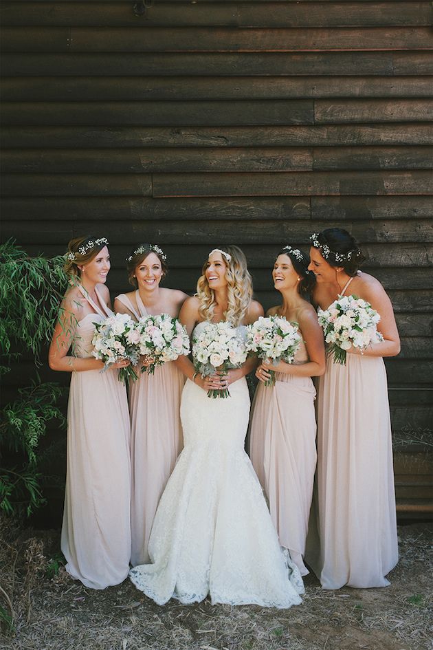 bride and bridesmaids in blush pink full length dresses having a giggle