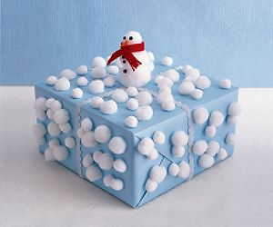 Glue pom-poms in various sizes to a blue wrapped package. Stack and glue large p...